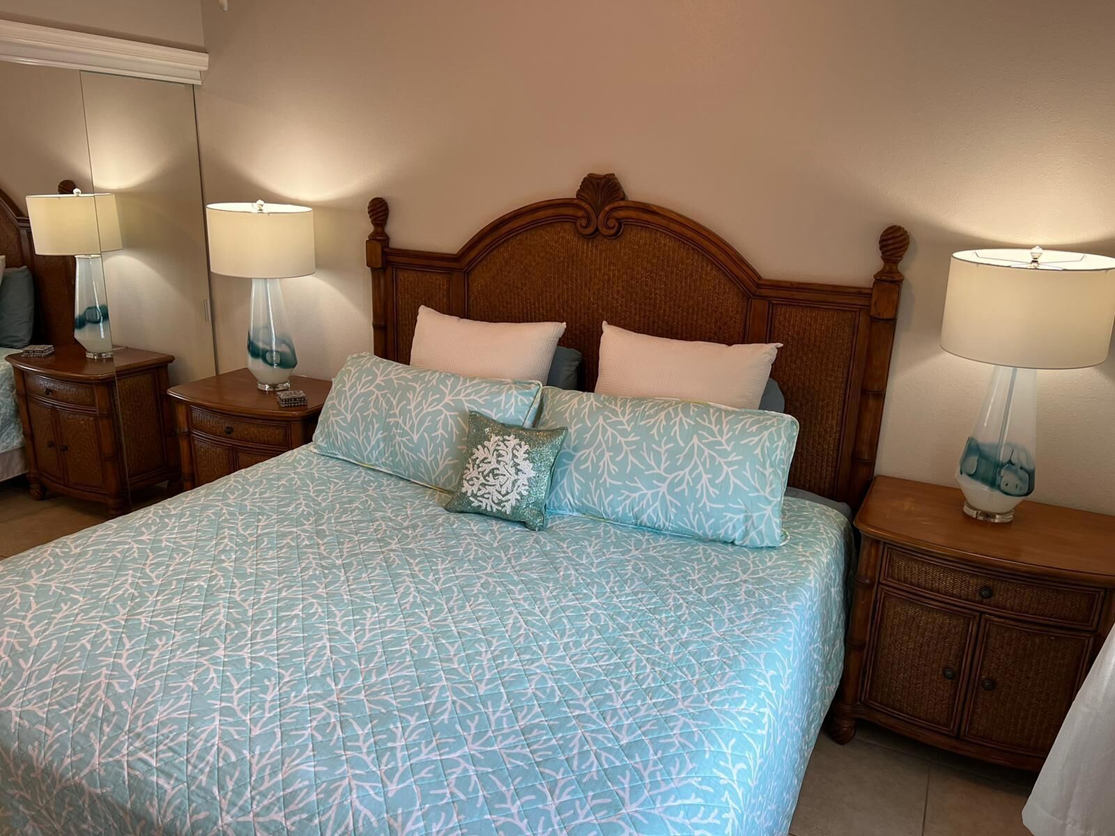 A neatly made bed with a patterned bedspread, two bedside tables with lamps, and a wooden headboard.