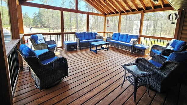 A covered outdoor seating area with wicker furniture and a wooden deck.