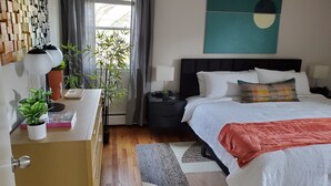 A modern bedroom with a bed, bedside tables, a desk with a lamp, and a wall art piece.