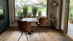 A modern kitchen with a large window, two chairs, a table, and a small side table with a lamp. - Small black forest lodge (Efringen-Kirchen)