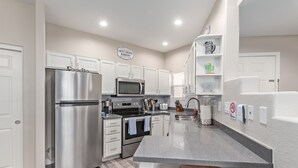 A modern kitchen with stainless steel appliances, white cabinetry, and a granite countertop. - Desert retreat, 3 pools, free parking, PAC MAN, Pickleball, Basketball, Internet (Phoenix)