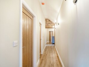 Un couloir avec des portes en bois et un mur en briques apparentes.