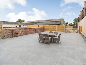 A courtyard with a stone floor, wicker furniture, and a brick wall.