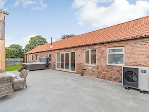 A brick building with a tiled roof, a hot tub, and an air conditioning unit.