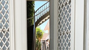A white door with a metal gate, a staircase, and a tiled floor leading to a building. - Unique Flat (Athens)