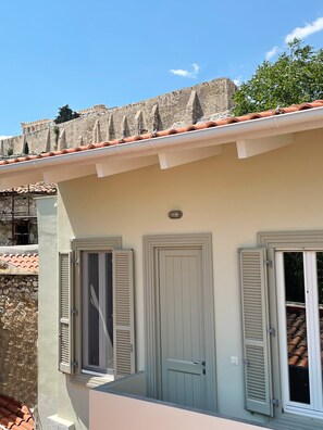 A building with a stone wall, a tiled roof, and a balcony with a door and window. - Unique Flat (Athens)