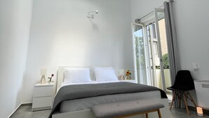 A modern bedroom with a skylight, a bed with a grey blanket, a bedside table with a lamp, and a bench. - Unique Flat (Athens)