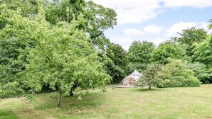 A tent-like structure in a grassy area surrounded by trees.