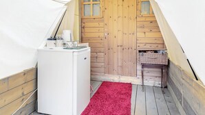 A small, enclosed space with a white refrigerator, a wooden door, and a red carpet.