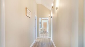A hallway with light-colored walls, wooden flooring, and a framed picture on the left. - Dip Tub Den - UK35989 (Skerne, near Driffield)