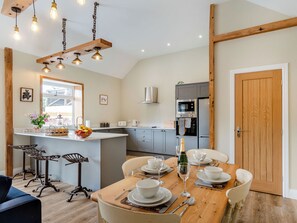 A modern kitchen with grey cabinets, a wooden island, and a dining area set for six with a wooden table and chairs.