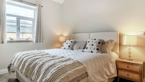 A bedroom with a bed, bedside lamps, a window, and a nightstand. - Dip Tub Den - UK35989 (Skerne, near Driffield)