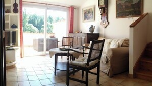 Ein Wohnzimmer mit einer Couch, zwei Sesseln, einem Tisch, einer Uhr und einem Bild an der Wand.