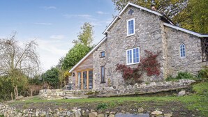 A stone house with a wooden porch and a stone wall in front. - 1 bedroom accommodation in Llansilin, near Oswestry (Llansilin, near Oswestry)