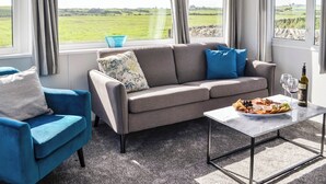 Een moderne woonkamer met een grijze bank, een blauwe fauteuil en een marmeren salontafel.