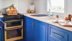 Een keuken met blauwe kastjes, een fornuis en een raam.