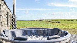 Een hottub met uitzicht op een groen veld en een stenen muur.