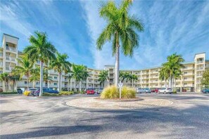A multi-story hotel with a central courtyard featuring palm trees and a circular driveway.