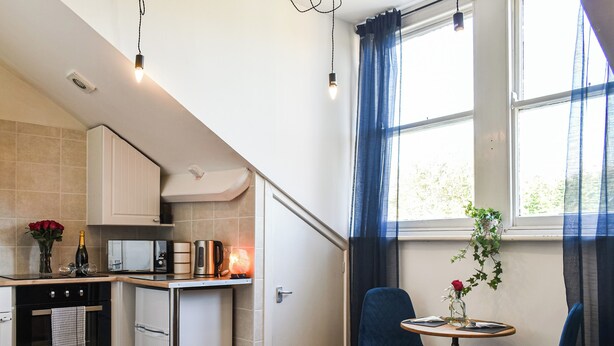 A compact kitchen with a microwave, kettle, and a small dining area with two chairs and a table. - St Martins Square Apartment 3 (Scarborough)