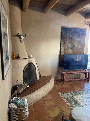 A living room with a fireplace, a television on a stand, a woven basket, and a patterned rug. - Relaxing Arroyo Seco Vacation Home with Beautiful Views (Valdez)