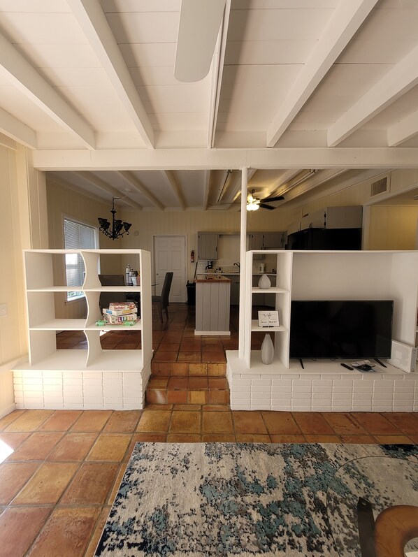 A living room with a fireplace, TV, and bookshelves. There is a kitchen in the background. - Vero Beach Hideaway- 5-minute drive from beach (Vero Beach)