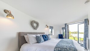 A bedroom with a bed, bedside table, and a view of a lake. - 1 bedroom accommodation in Hawton, near Newark (Hawton, near Newark)