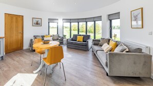 A spacious living area with a dining table, two sofas, and a large window offering a view of the outdoors. - 1 bedroom accommodation in Hawton, near Newark (Hawton, near Newark)