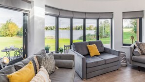A modern living room with large windows, a grey sofa, and a small table with cups. - 1 bedroom accommodation in Hawton, near Newark (Hawton, near Newark)