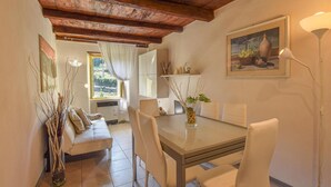 Un coin repas avec une table en verre, des chaises blanches, un canapé et un tableau au mur.