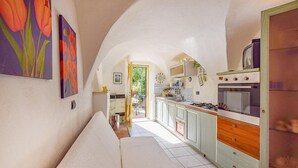 Un couloir étroit mène à une cuisine équipée d’une cuisinière, de placards et d’une porte.
