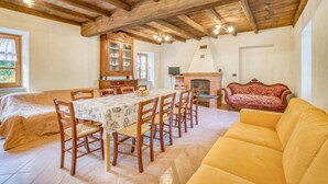 Un comedor con una mesa larga, sillas de madera, un aparador con puertas de cristal y una chimenea.