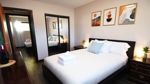 A hotel room with a large bed, bedside tables, a desk, and a wardrobe.