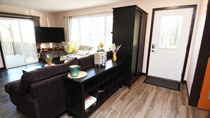 A living room with a dark-colored sofa, a flat-screen TV, a cabinet, and a door with a window.