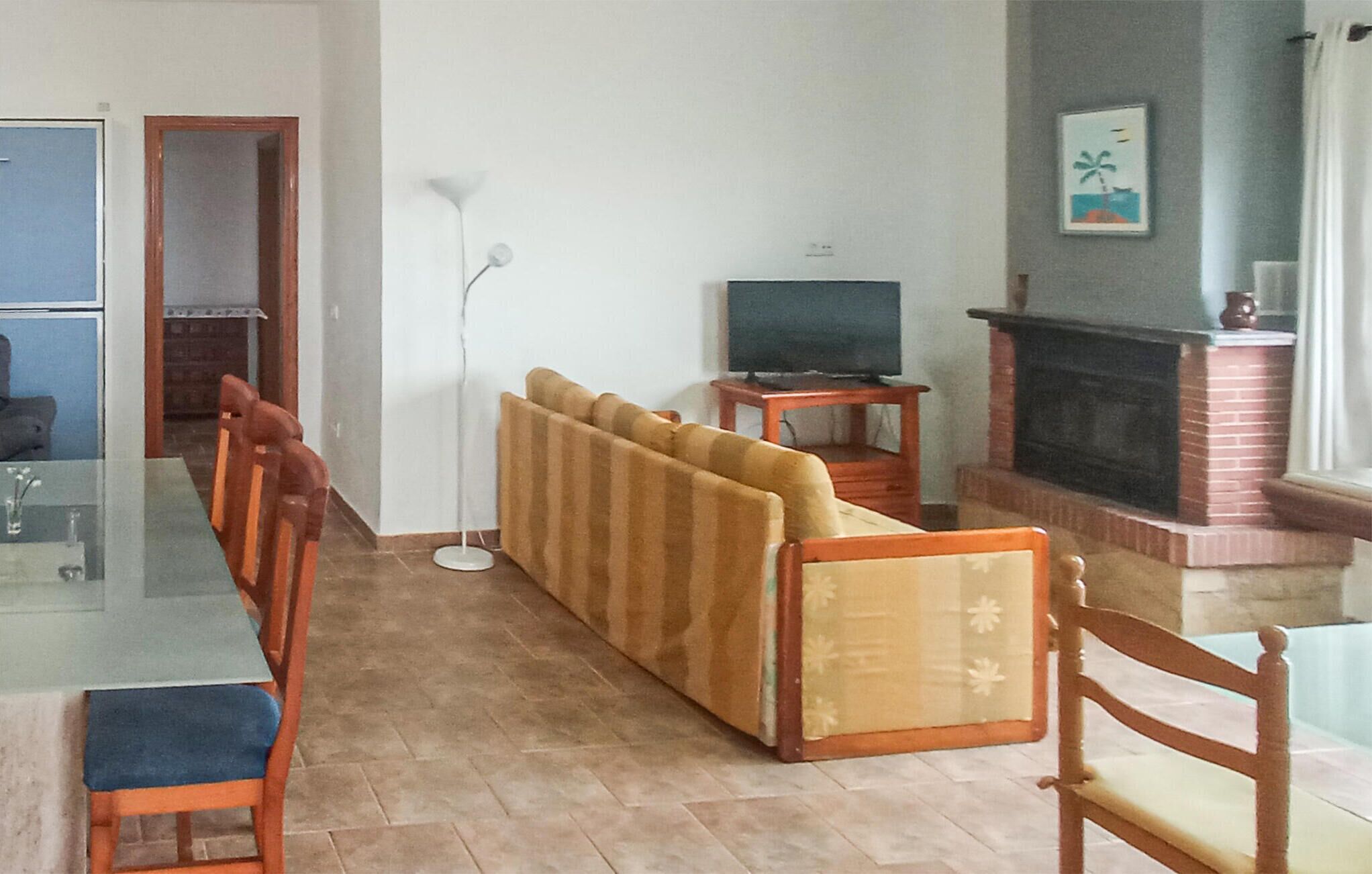 Un comedor con una mesa larga, asientos acolchados, un televisor y una chimenea.