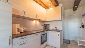 Een moderne keuken met lichte houten keukenkastjes, roestvrijstalen apparatuur en een inbouwoven.