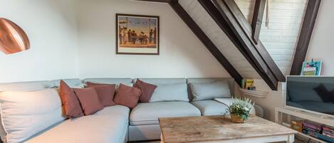 A living room with a light grey sofa, a wooden coffee table, and a framed picture on the wall.