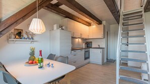 Een moderne keuken met een eethoek, houten balken en een spiltrap.