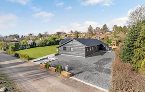 A modern single-story house with a grey exterior, a driveway, and a well-maintained lawn.