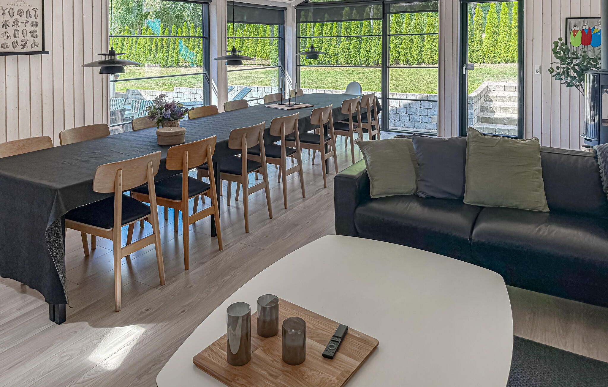 Een eethoek met een lange tafel, stoelen en een bank. Er staan kaarsen en een afstandsbediening op een tafel.