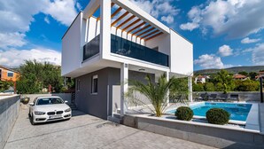 A modern two-story house with a swimming pool, a car parked in the driveway, and a clear blue sky. - Awesome apartment in Obrovac (Obrovac)