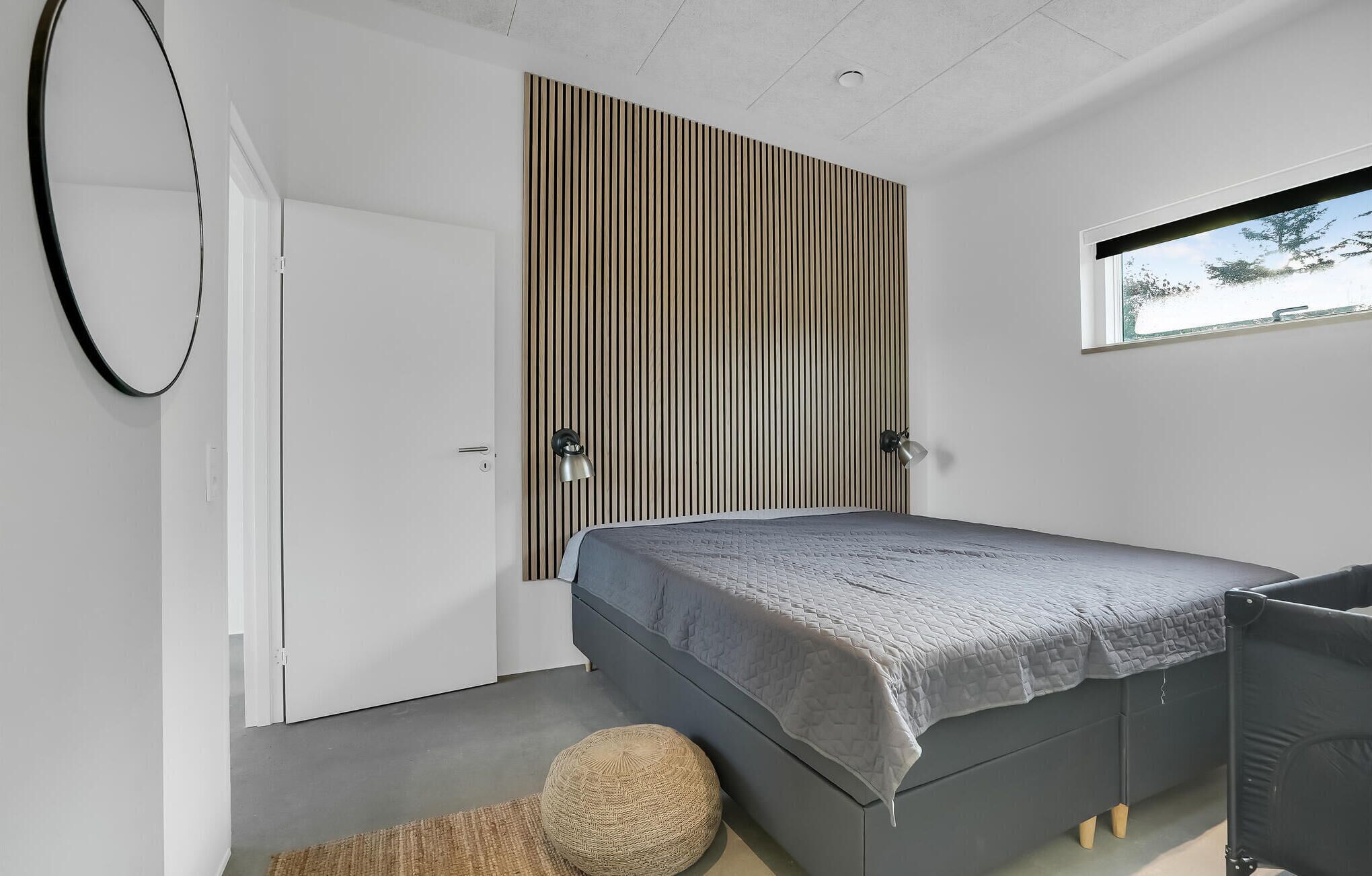 Una camera da letto con un letto, una finestra, una porta e una parete con linee verticali.