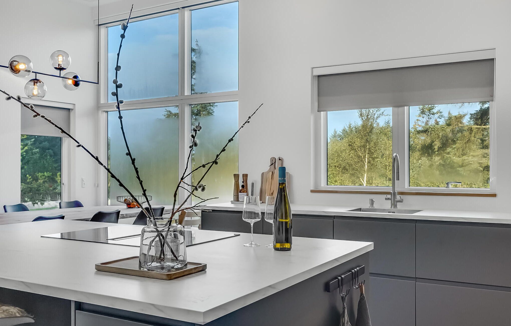 A modern kitchen with a large island, a sink, and a window overlooking greenery.
