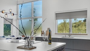 A modern kitchen with a large island, a sink, and a window overlooking greenery. - 4 bedroom gorgeous home in Esbjerg V (Esbjerg V)
