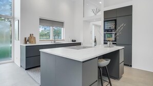 A modern kitchen with a central island, dark cabinetry, and a large window providing natural light. - 4 bedroom gorgeous home in Esbjerg V (Esbjerg V)