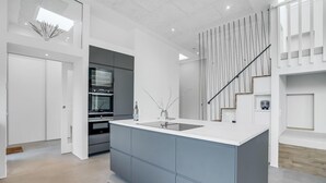 A modern kitchen with a central island, built-in appliances, and a staircase with a unique railing design. - 4 bedroom gorgeous home in Esbjerg V (Esbjerg V)