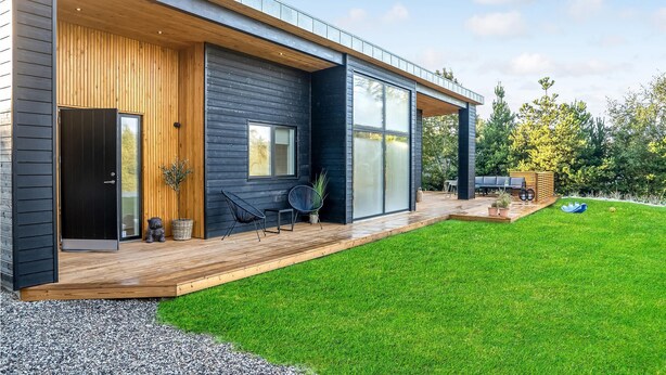 A modern house with a wooden deck, a large sliding glass door, and a well-maintained lawn. - 4 bedroom gorgeous home in Esbjerg V (Esbjerg V)