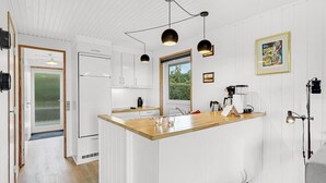 A modern kitchen with white cabinetry, a wooden countertop, pendant lighting, and a view of greenery outside. - Awesome home in Faaborg with WiFi (Faaborg)
