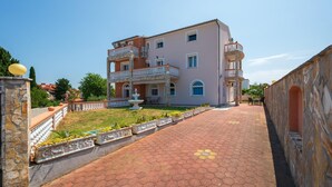 A two-story building with a balcony, a fountain, and a paved walkway. - Nice apartment in Pula with WiFi (Pula)