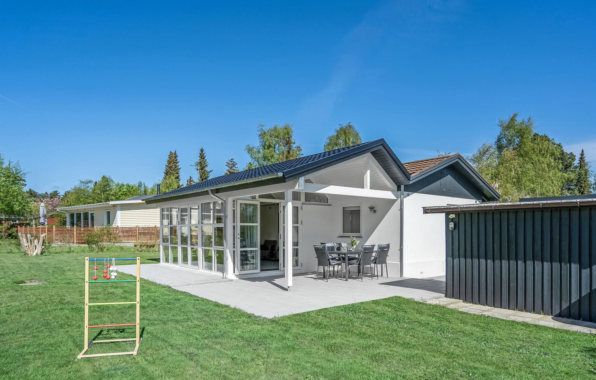 A modern house with a covered patio, a fenced yard, and a shed.