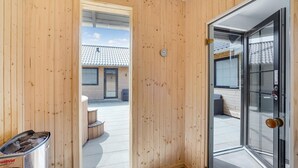 Een houten buitenmuur met een glazen deur naar een overdekt terras.